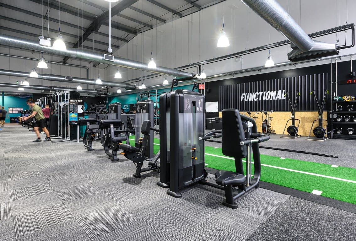 PureGym Bromsgrove Retail Park: Gym studio with weight machines, free weights, turf training area, and industrial decor.