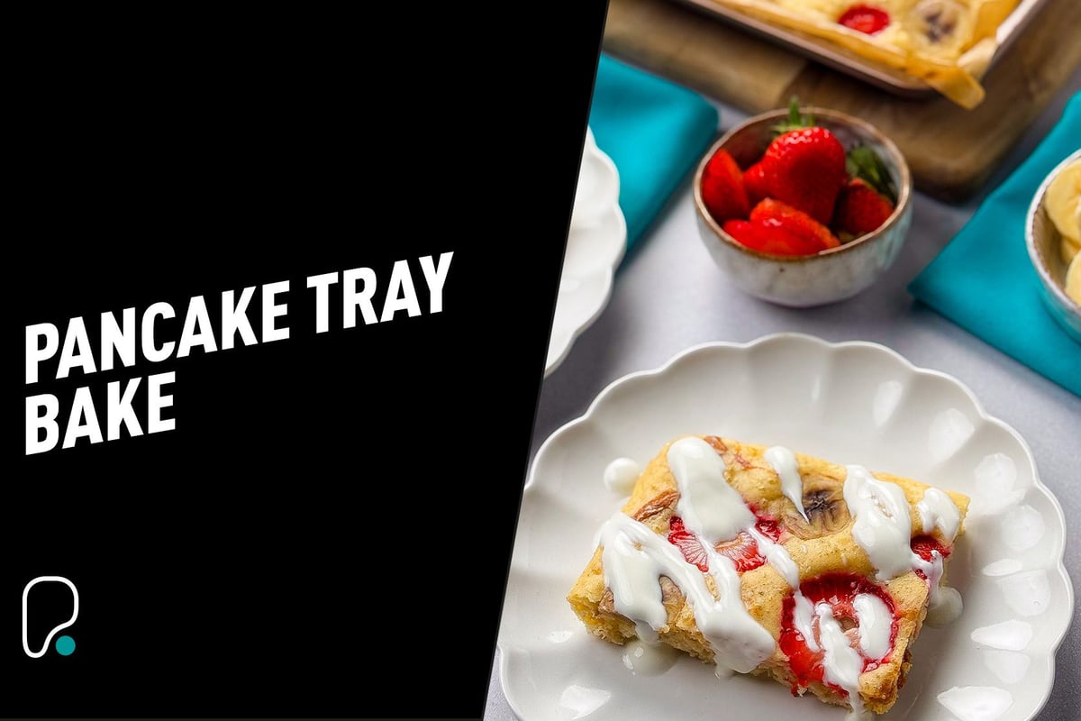 Square pancake slice with strawberries and banana drizzled with white sauce