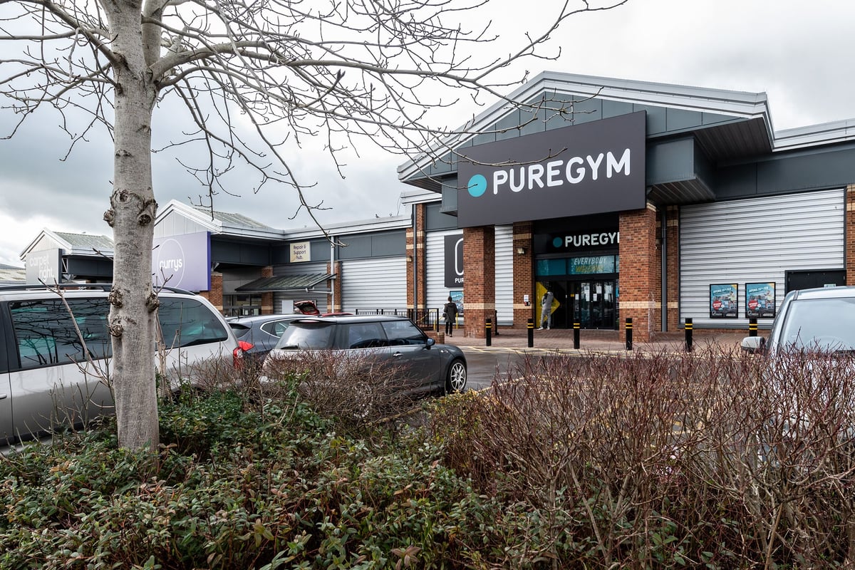 PureGym Yeovil Houndstone Retail Park: Gym exterior with parking lot, tree branches in foreground.