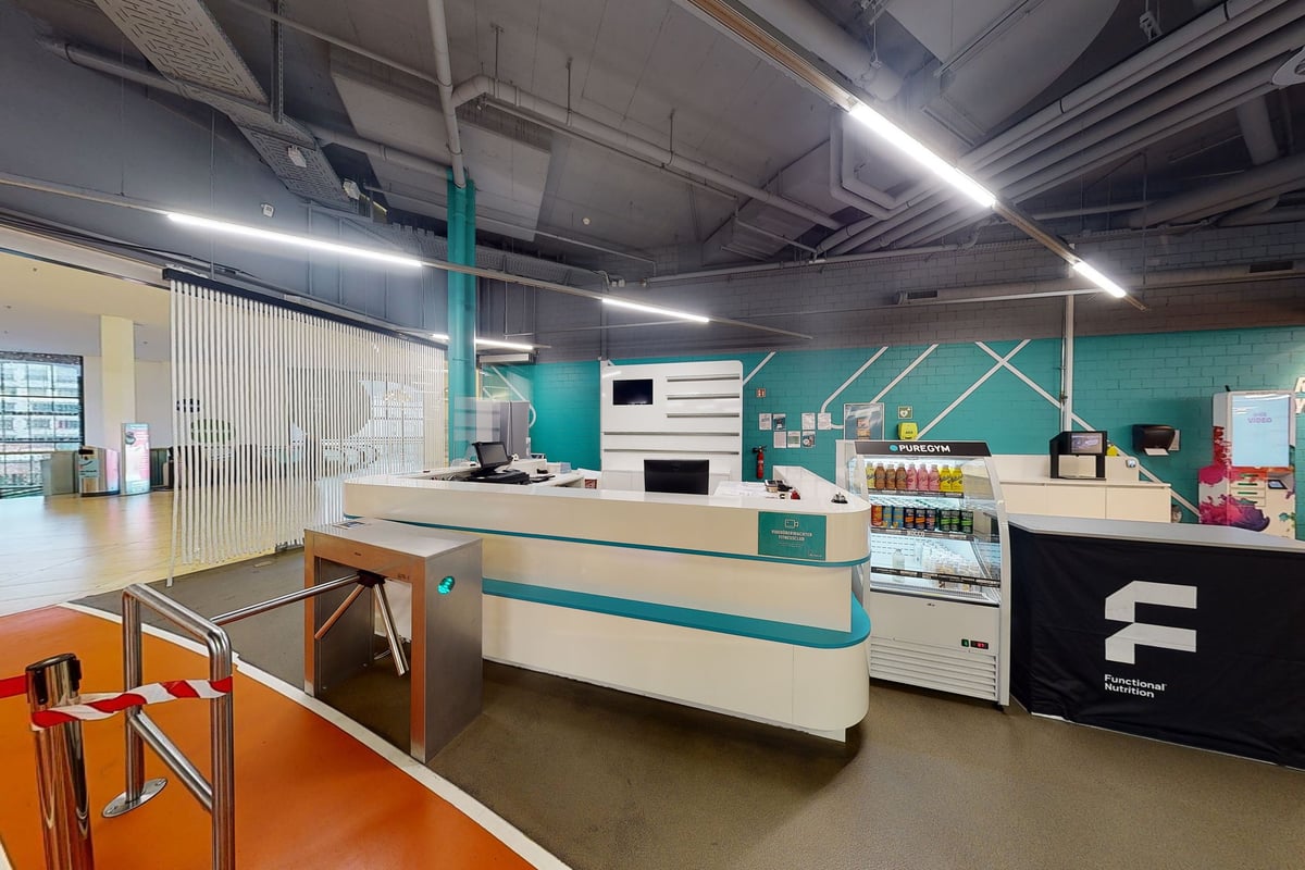 PureGym Winterthur Töss: Studio de remise en forme avec des équipements modernes, des armoires de rangement, des tables de travail et des murs d'accent bleu sarcelle.