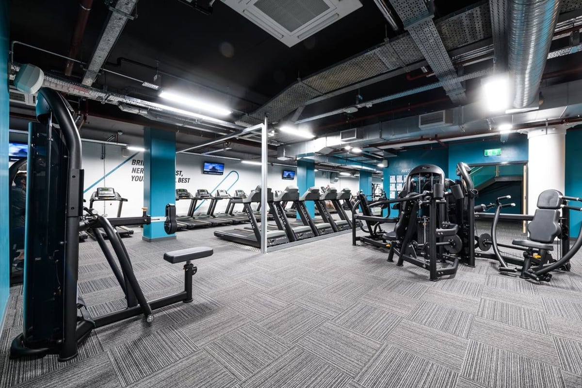PureGym London East India Dock: Rows of treadmills, ellipticals, weight machines in a dimly lit gym.