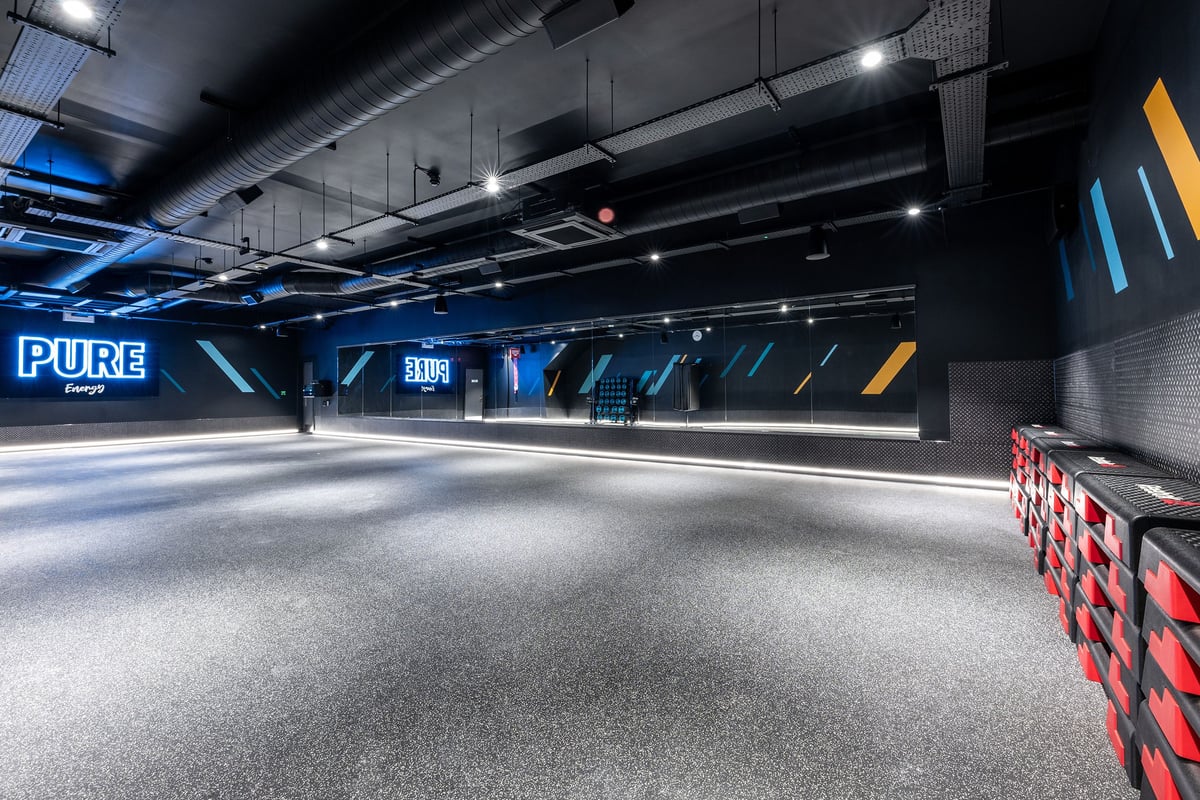 PureGym Liverpool Edge Lane: Track with neon lighting, Pure Energy branding, rubberized flooring.