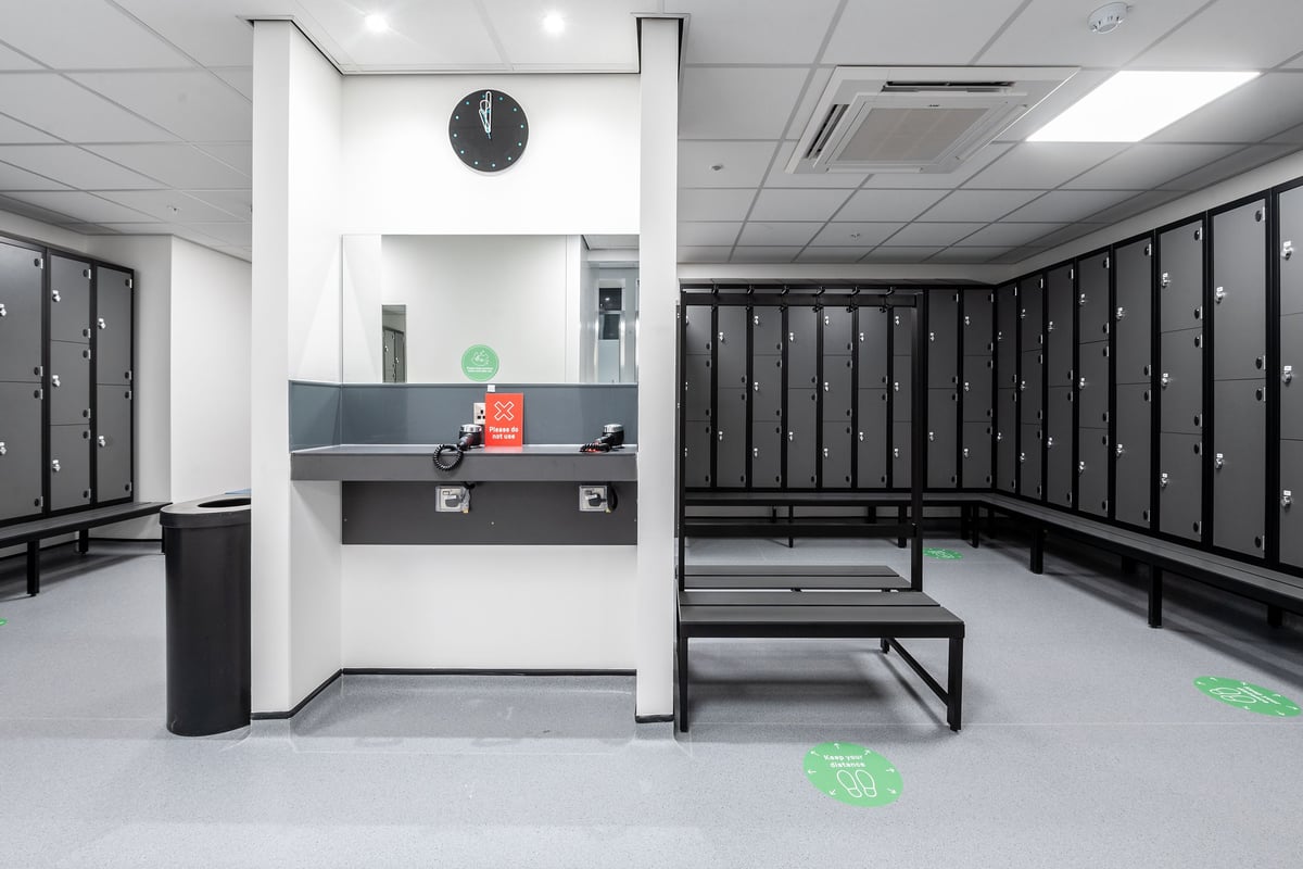 PureGym Maidstone The Mall: Rows of lockers, benches, and a reception counter in a gym changing area.