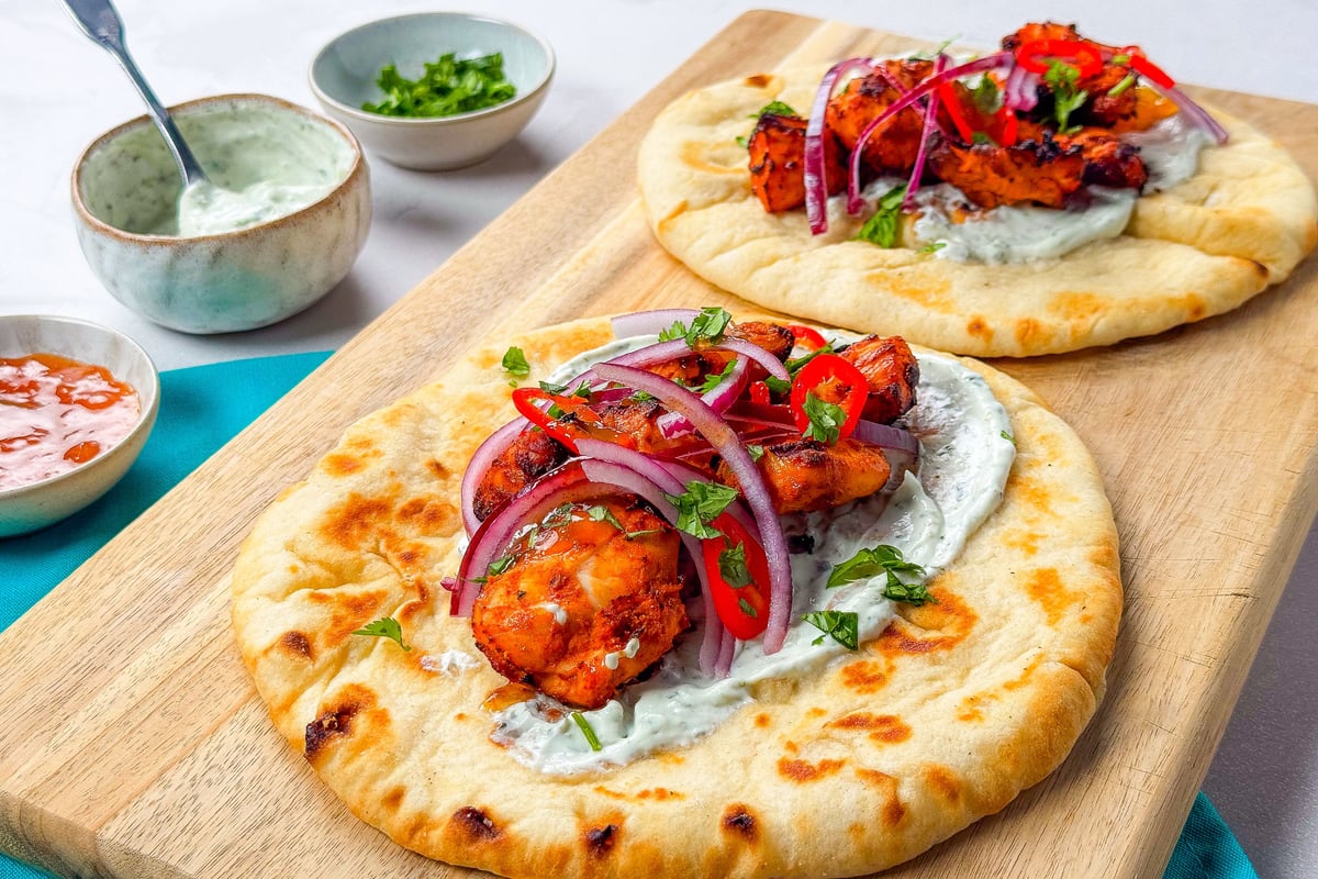 Flatbreads topped with grilled chicken, yoghurt sauce, red onion, chilli, and herbs