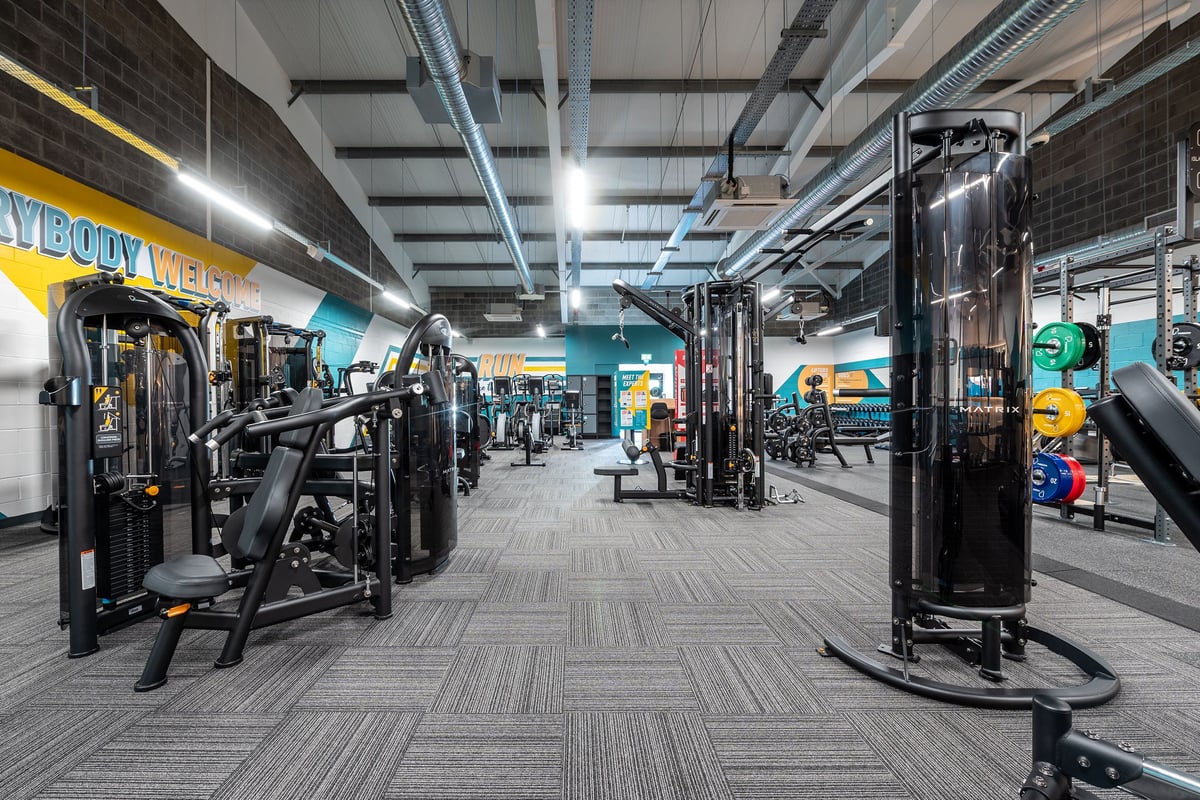 PureGym Aberdare: Rows of cable machines, weight stacks, rubberized flooring, and bright lighting.