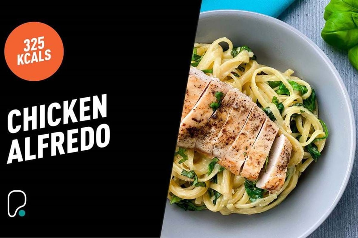Grilled chicken breast slices on creamy Alfredo pasta with spinach in a bowl