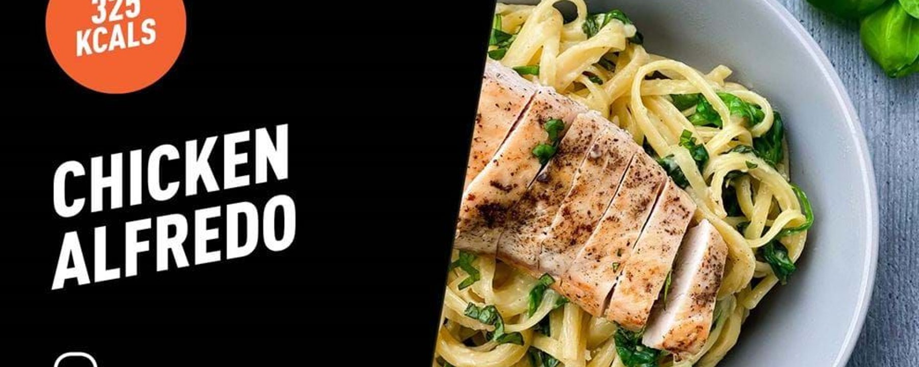 Grilled chicken breast slices on creamy Alfredo pasta with spinach in a bowl