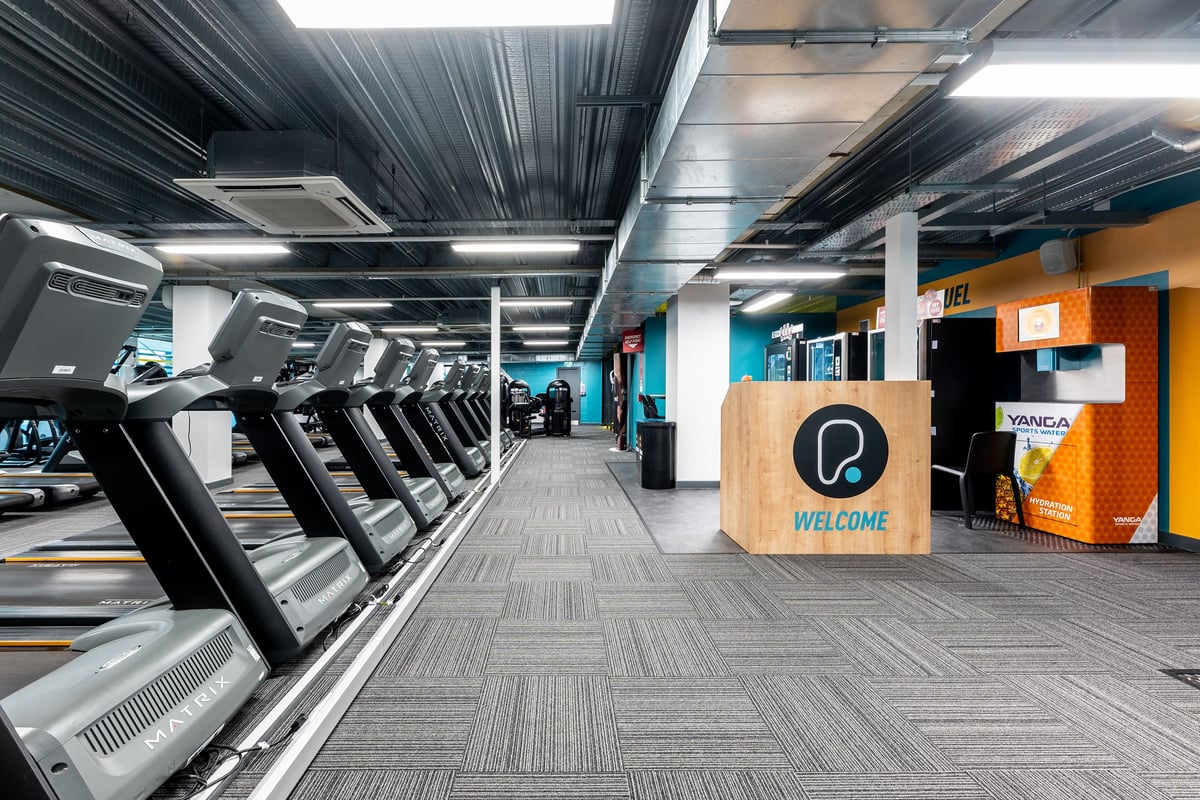 PureGym Newcastle Eldon Garden: Rows of treadmills, welcome sign, and ventilation ducts create a modern gym ambience.