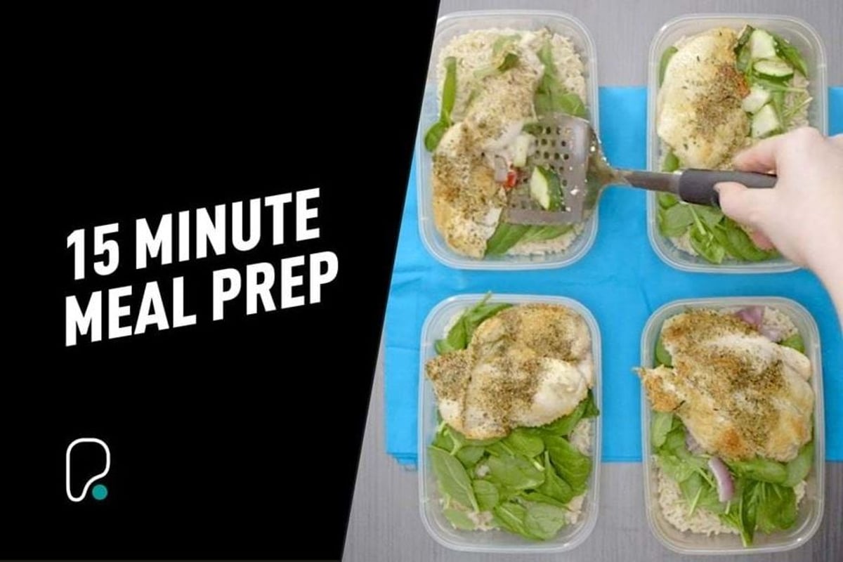 Four meal prep containers with chicken, green vegetables and seasoning on blue mat