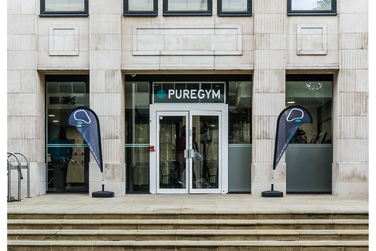 PureGym London Holborn: Front exterior of a Pure Gym facility, with signage, stairs, and branded flag banners.