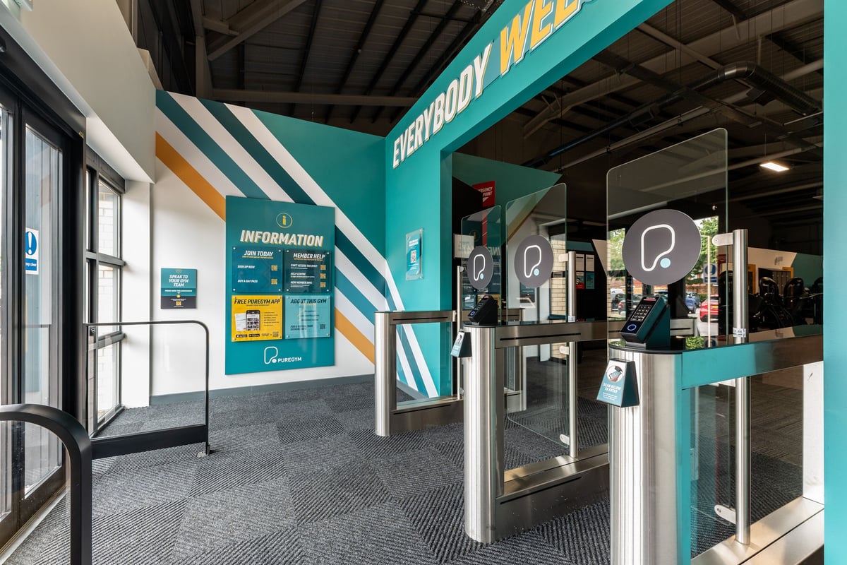 PureGym Byfleet: Reception area with kiosks, signage, and queue barriers.