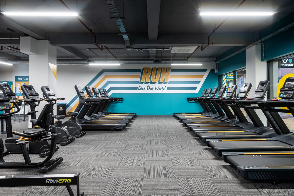 PureGym London Kingston: Rows of treadmills and motivational wall mural in a well-lit gym studio.