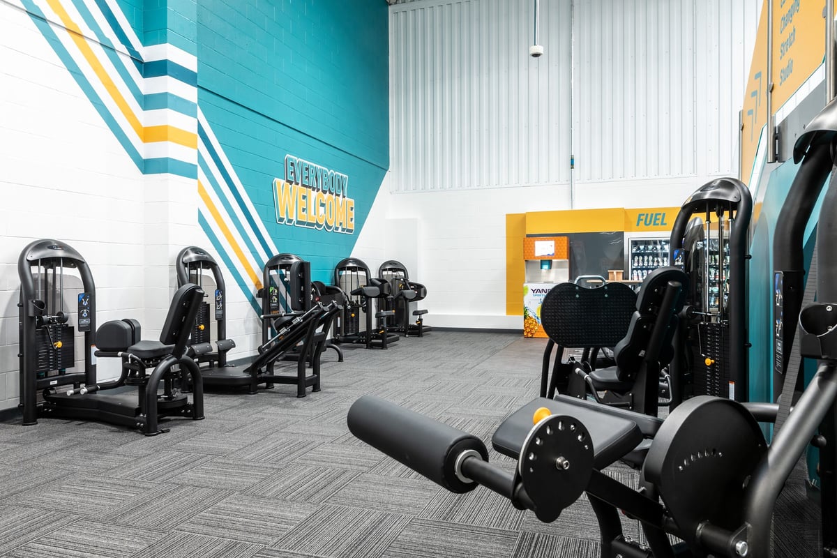 PureGym Grantham Discovery Retail Park: Rows of exercise machines, free weights, and a wall with colourful chevron stripes.