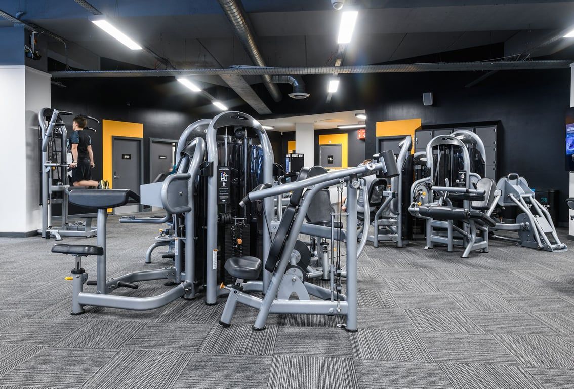 PureGym Bournemouth The Triangle: Rows of weightlifting machines, benches, and rubberized flooring in a dimly lit gym studio.