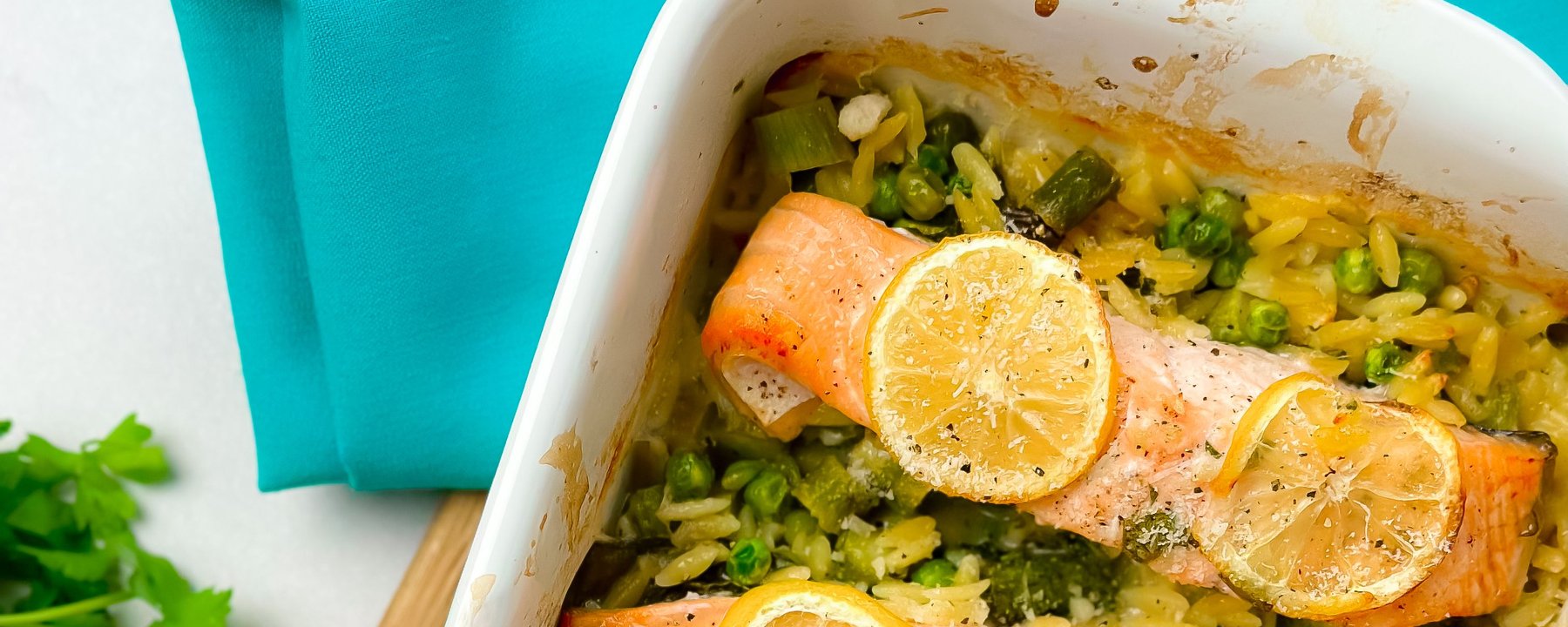 Baked salmon fillets with lemon slices on orzo rice with peas and vegetables