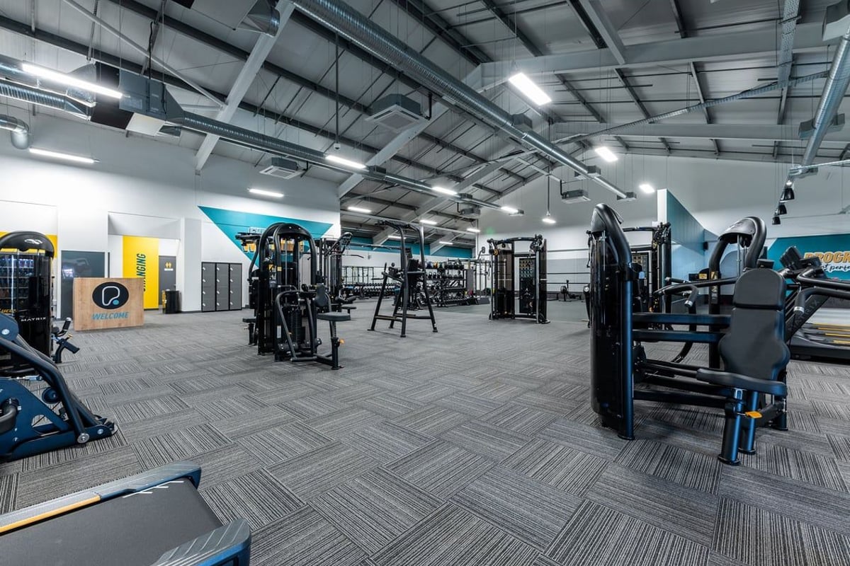 PureGym Uttoxeter: Resistance machines, squat racks, free weights, benches, patterned rubberized flooring in a gym studio.