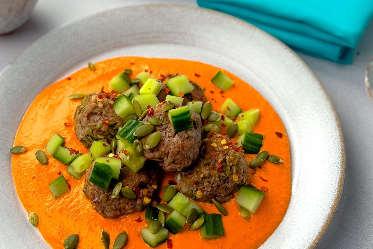 Meatballs topped with spring onion and chilli flakes on orange sauce