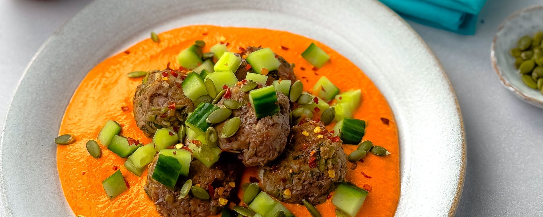 Meatballs topped with spring onion and chilli flakes on orange sauce