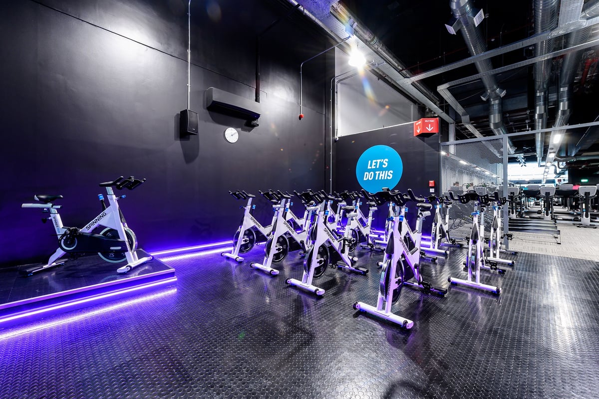 PureGym Hemel Hempstead: Rows of stationary bikes illuminated by neon purple lighting in a modern gym studio.