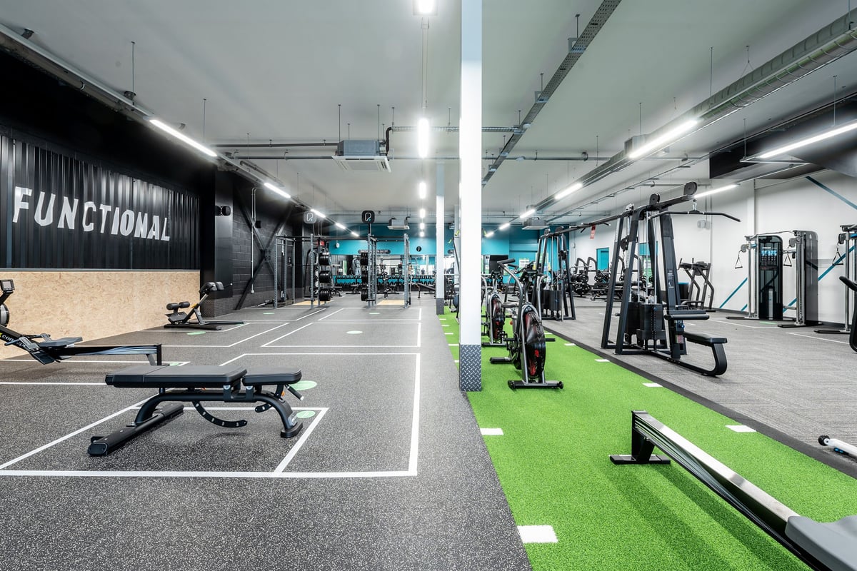 PureGym Birmingham Longbridge: Turfed area, resistance machines, benches, free weights, rubberized flooring in a modern gym.