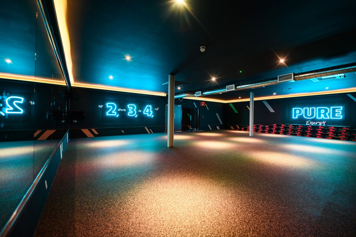 PureGym Telford: Fitness studio with dark walls, mirrors, and stacks of step platforms against the far wall.