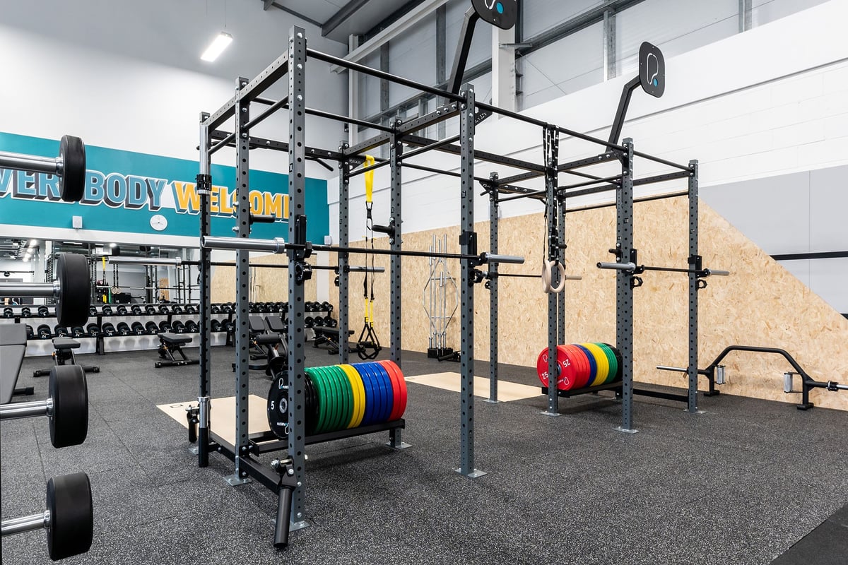 PureGym Galashiels: Power racks, barbell setups, bumper plates, and rubberised flooring in a weight training area.