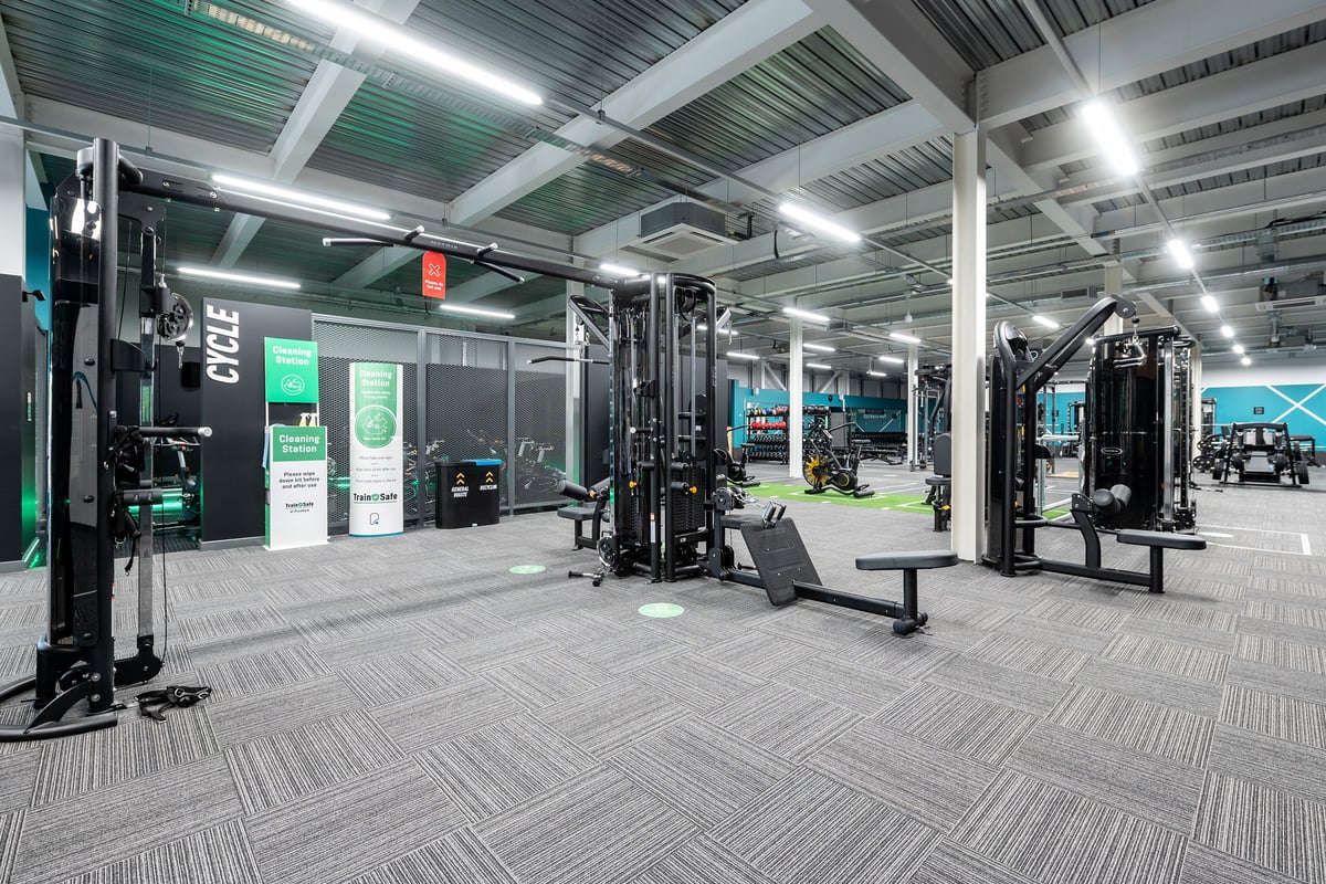 PureGym Andover: Gym studio with weight machines, squat racks, benches, and rubberized flooring in green and grey.