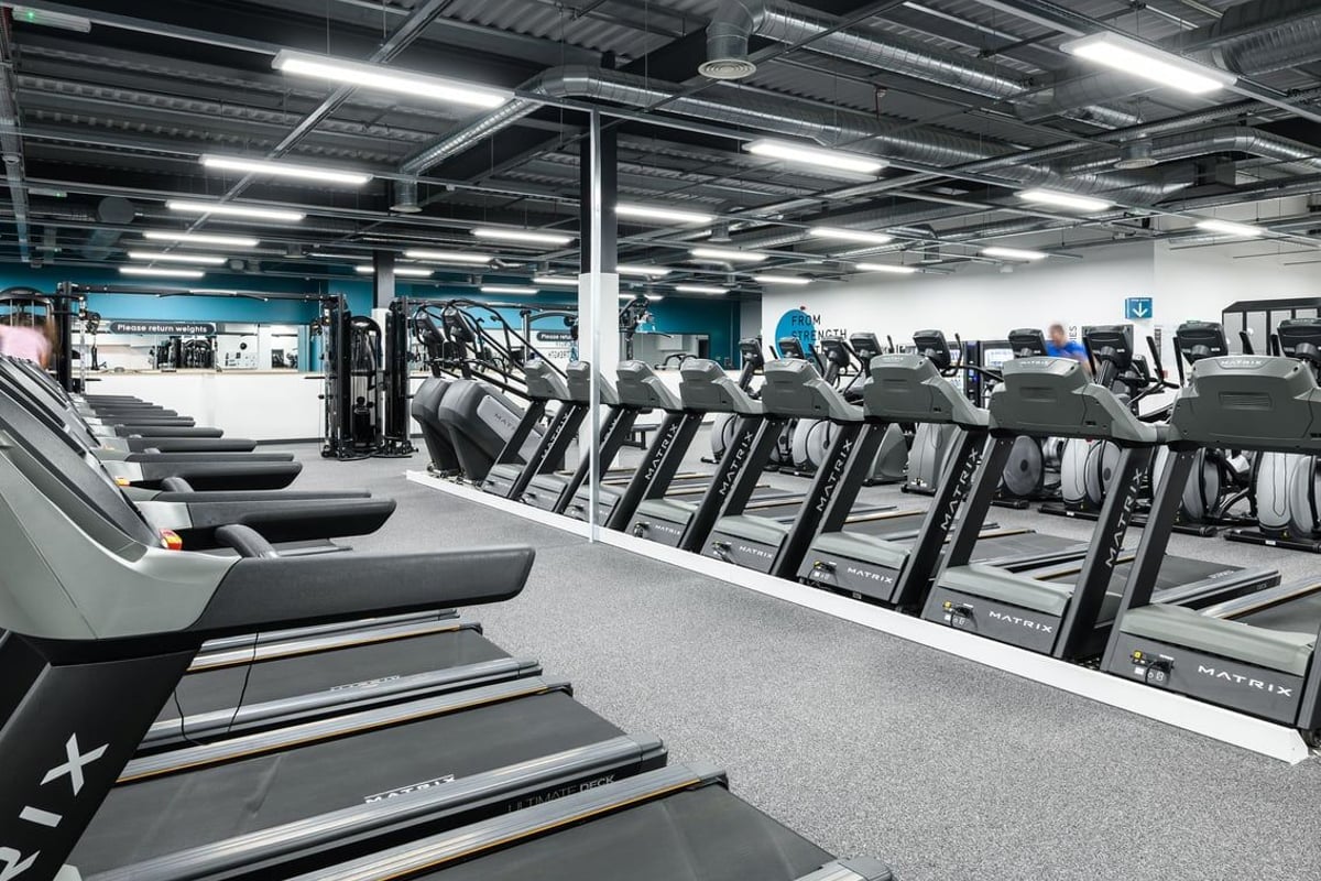 PureGym Newry: Rows of treadmills and cardio machines in a brightly-lit gym interior.