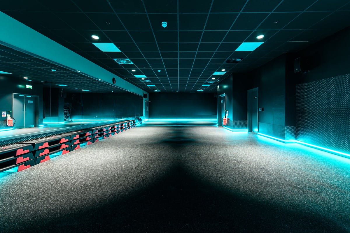 PureGym Hemel Hempstead: Rows of treadmills and exercise bikes in a dimly lit space with neon blue lighting.