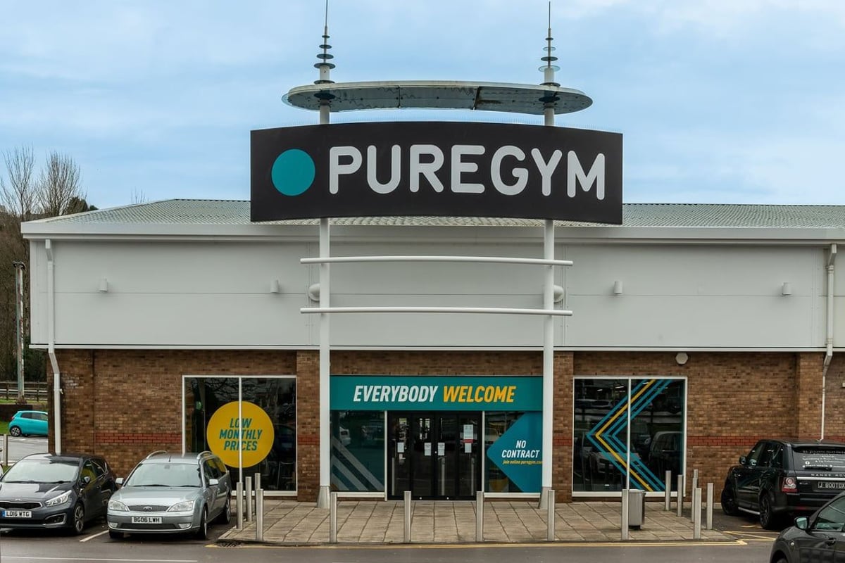 PureGym Llantrisant: PureGym storefront with branded signage, parked cars, and 'Everybody Welcome' window displays.