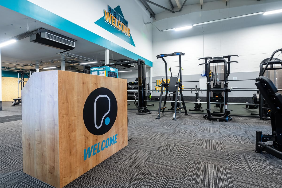 PureGym Linlithgow: Weight machines, benches, exercise equipment on rubberized flooring in a branded gym space.