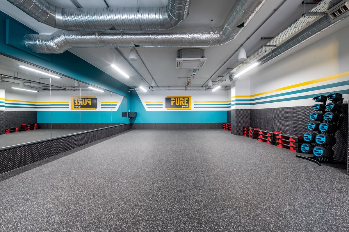 PureGym London Swanley: Weightlifting area with kettlebells, resistance bands, rubberized floors, and wall branding.