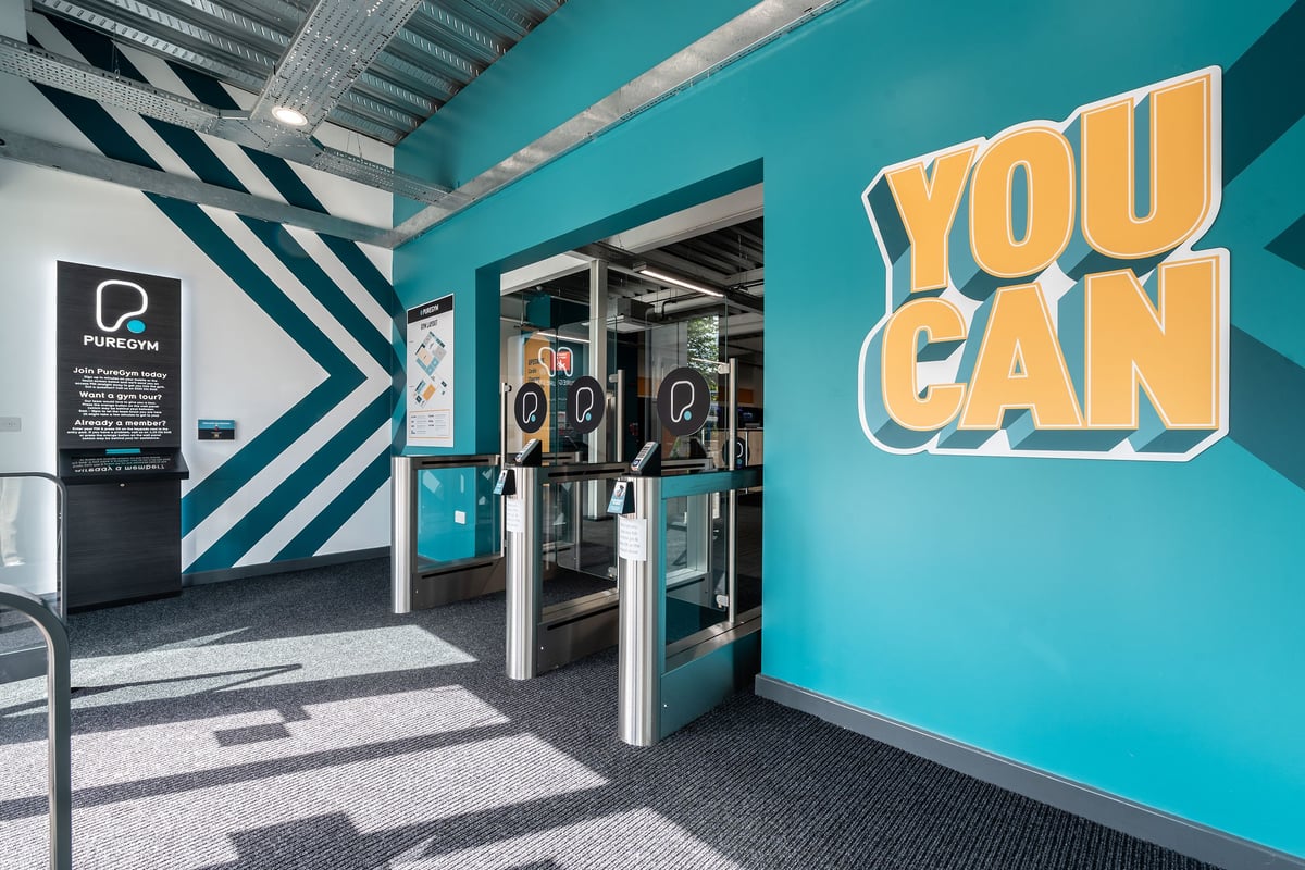 PureGym Cheshunt Brookfield Shopping Park: Teal-themed entrance with turnstiles, "You Can" signage, geometric patterns.