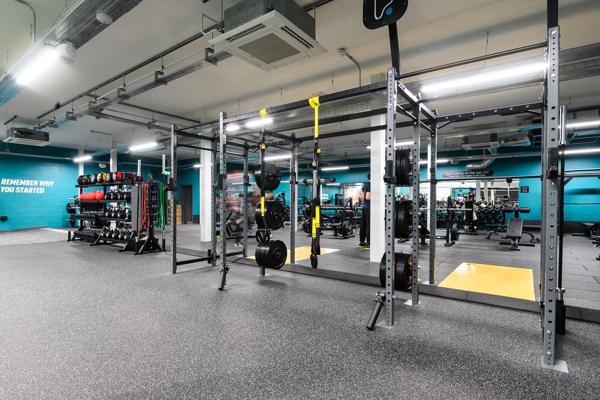PureGym Burgess Hill: Fitness area with squat racks, weight plates, bars, functional training rigs, and rubberized flooring.