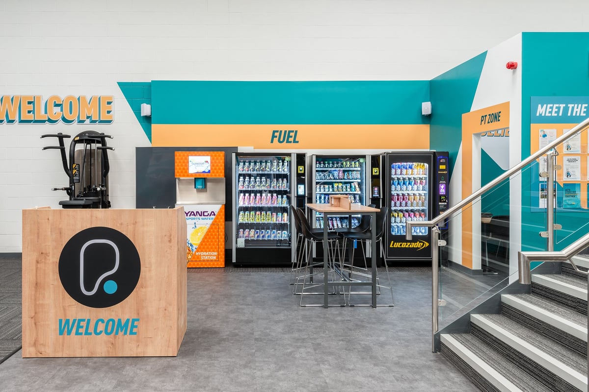 PureGym Cannock Orbital Retail Park: Vending machines stocked with beverages, welcome signage, and seating area.