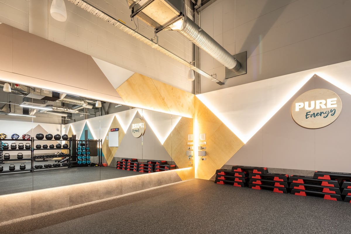 PureGym Wantage: Weight racks, kettlebells, rubberised flooring, geometric wall designs with 'PURE Energy' branding.