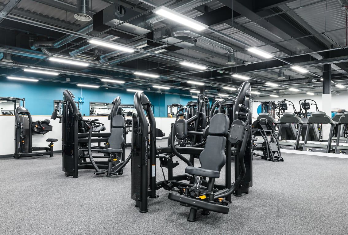 PureGym Newry: Weight machines, cable crossovers, benches, and mirrored walls in a brightly lit gym.