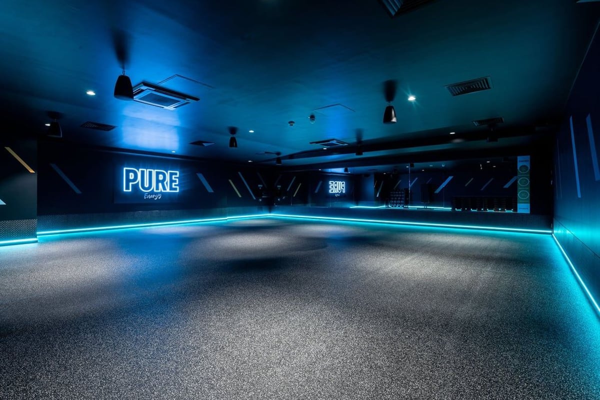 PureGym Milton Keynes Kingston Centre: Mirrored studio with neon Pure branding, rubberized flooring.