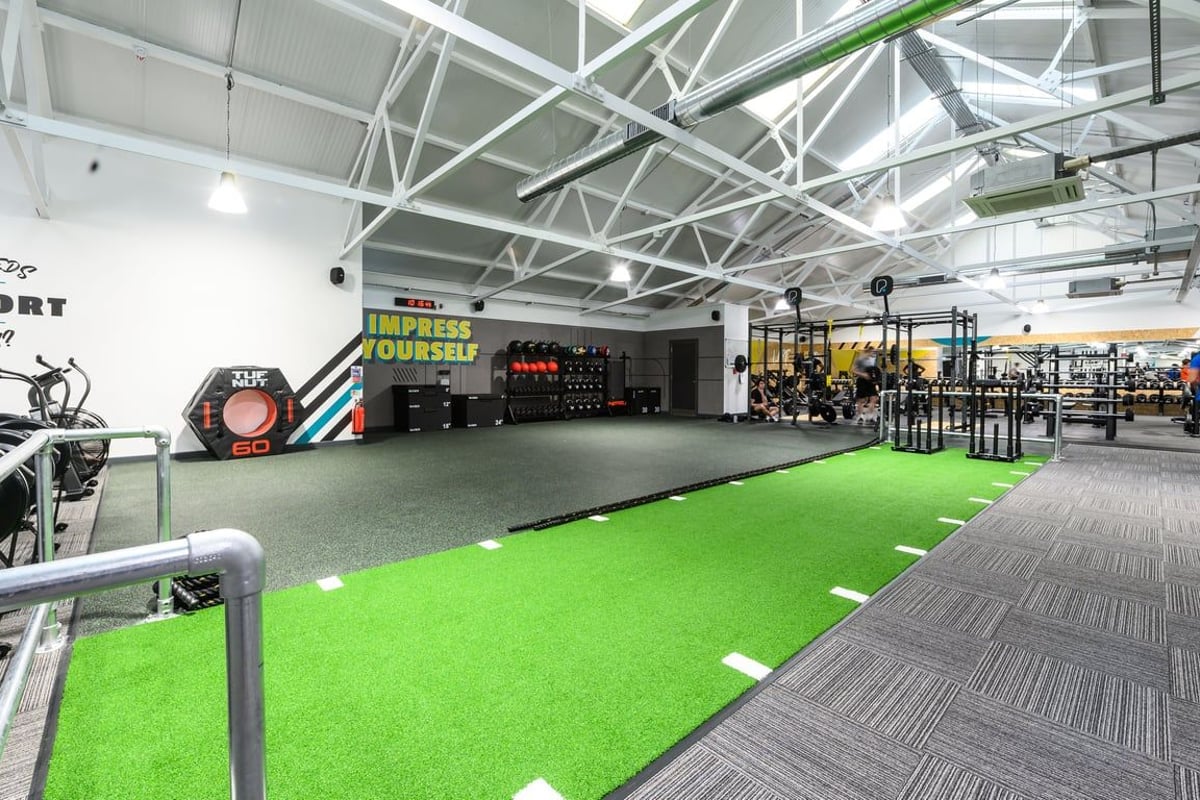 PureGym London East Sheen: Gym with turf area, weight racks, exercise balls, motivational signage, and rubberized flooring.