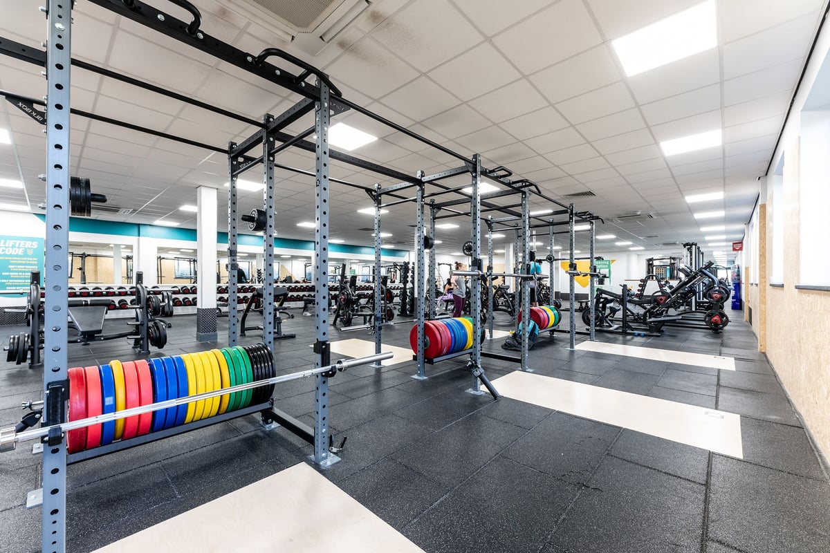 PureGym Livingston: Weight racks, colourful bumper plates, squat racks, benches, and rubberized flooring in a gym.