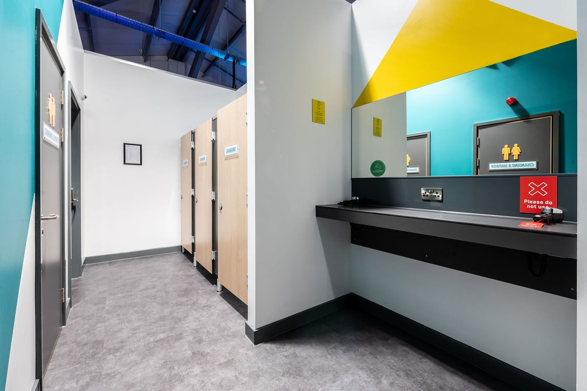 PureGym Stowmarket: Hallway with doors leading to changing rooms, reception desk with branding.