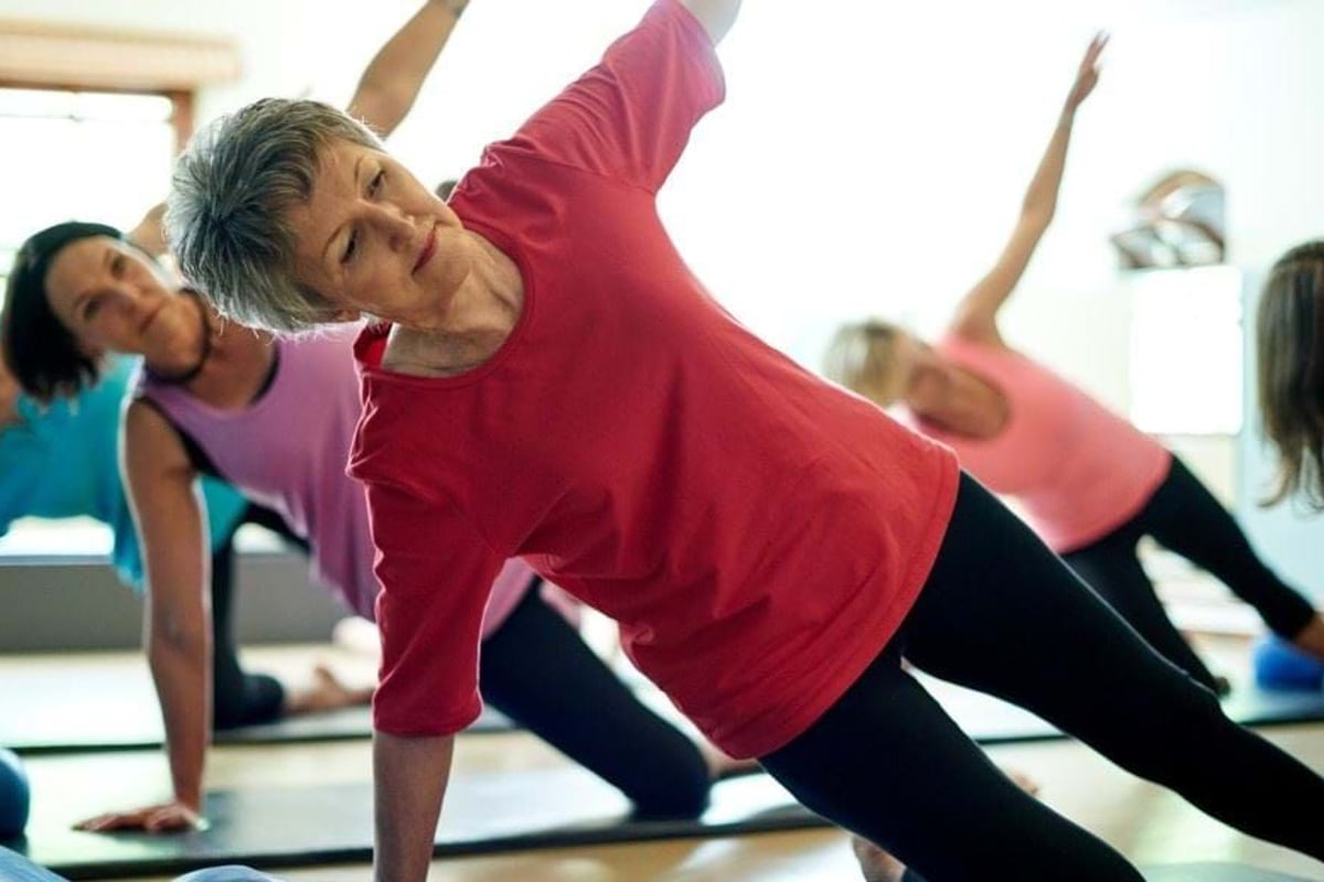 Group of women doing side plank exercise on yoga mats in a fitness studio