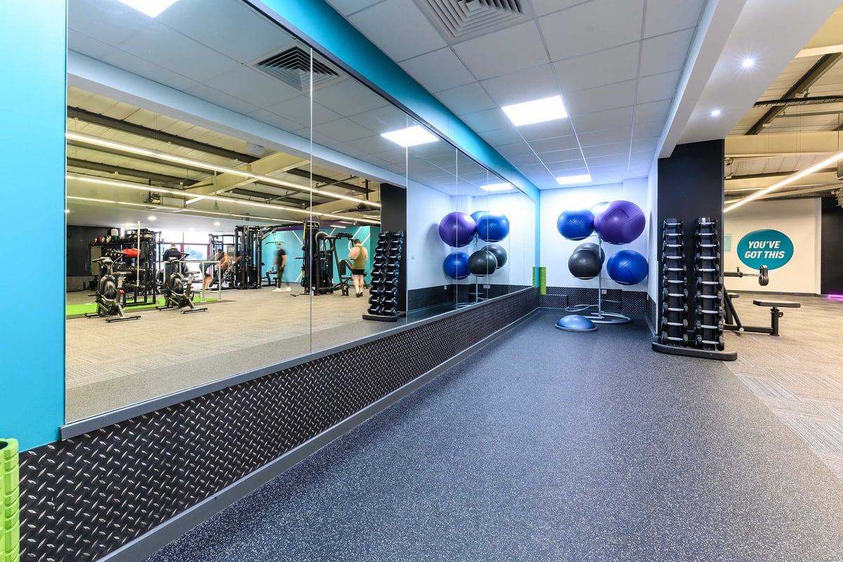 PureGym Poole: mirrored wall in front of a rubberised floor and racks of free weights in a gym studio