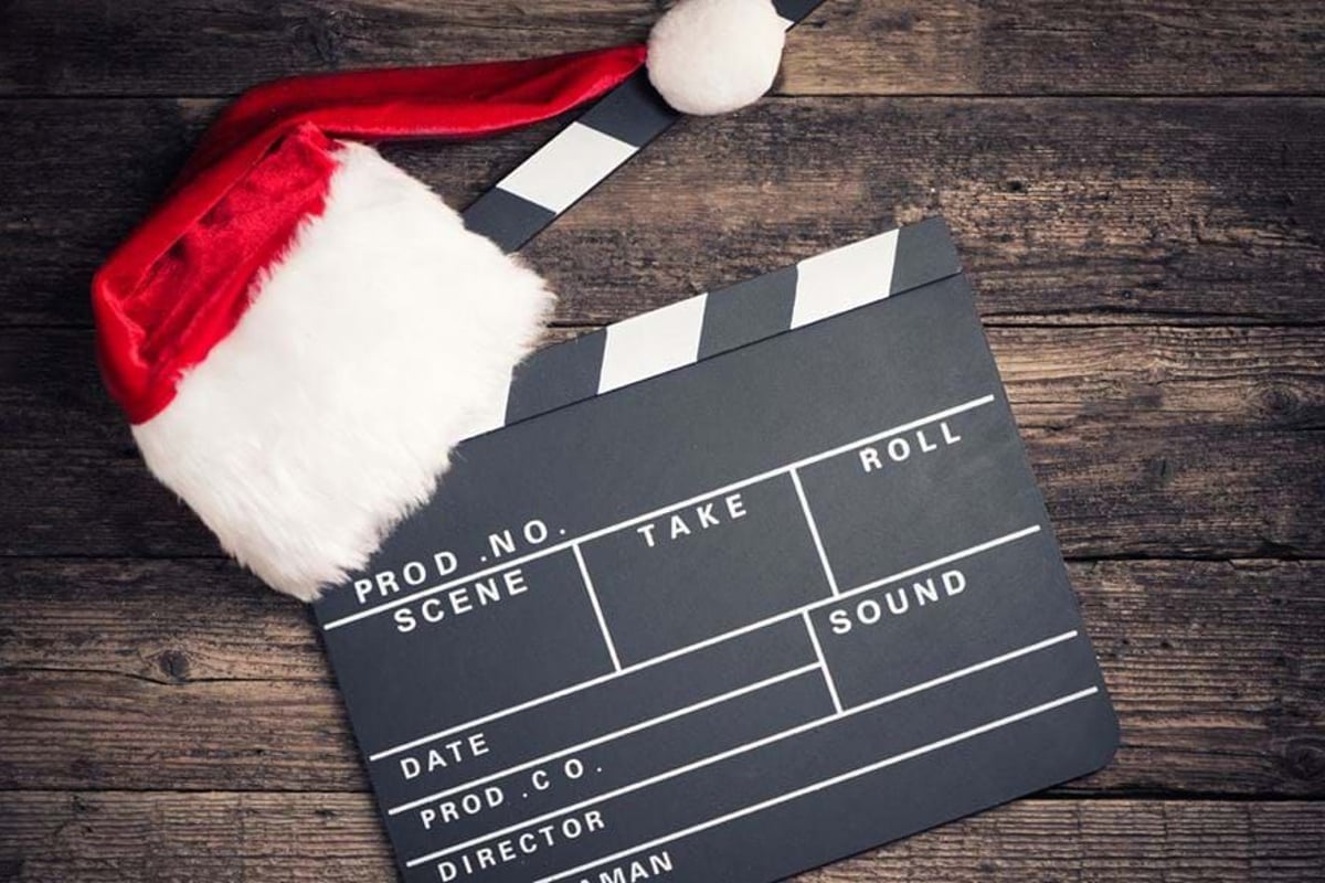 Clapperboard with a Santa hat on a wooden surface.