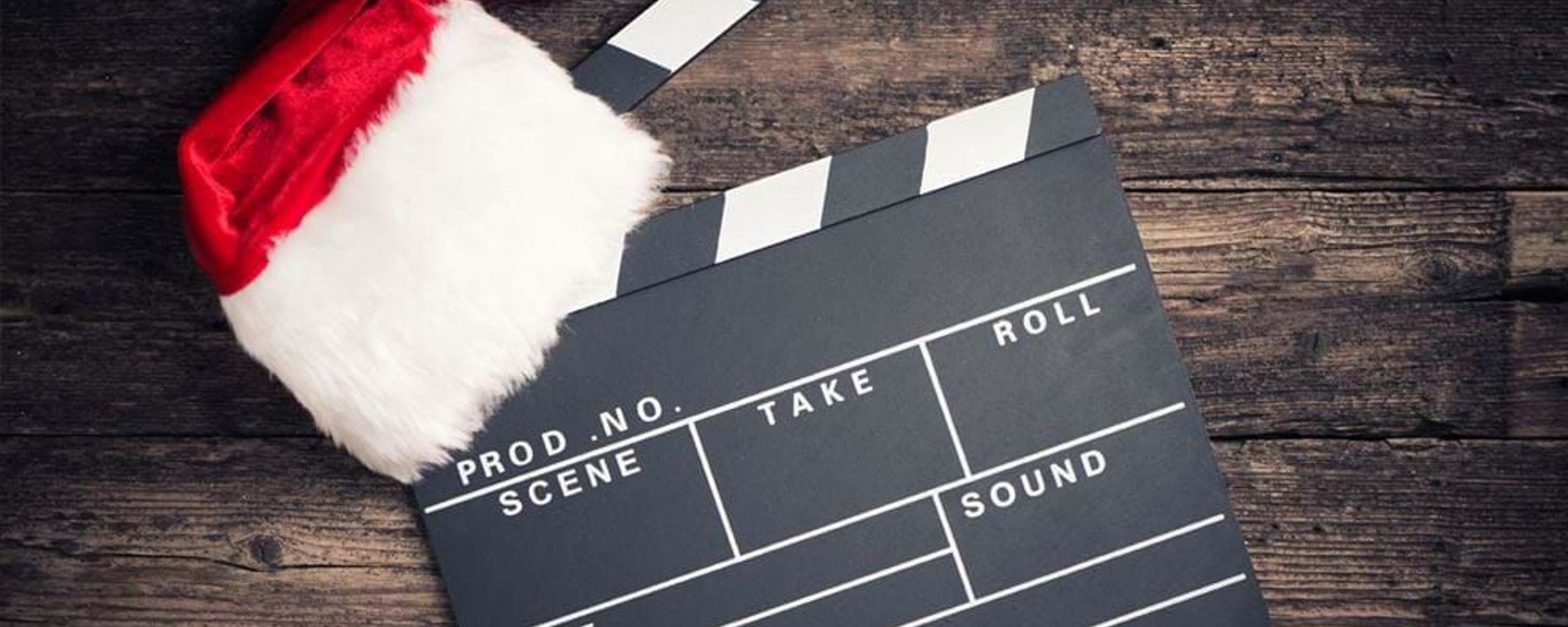 Clapperboard with a Santa hat on a wooden surface.