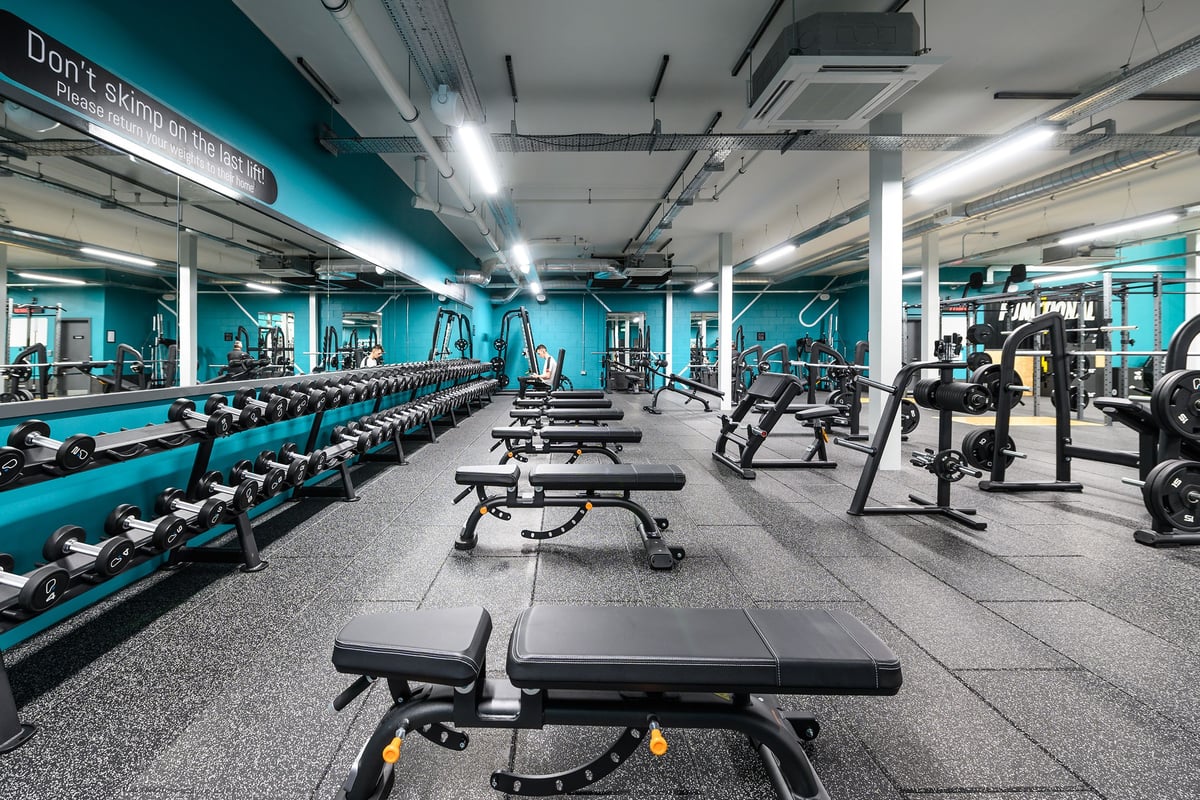 PureGym Burgess Hill: Resistance machines, free weights, benches, and rubberised flooring in a teal-coloured gym studio.