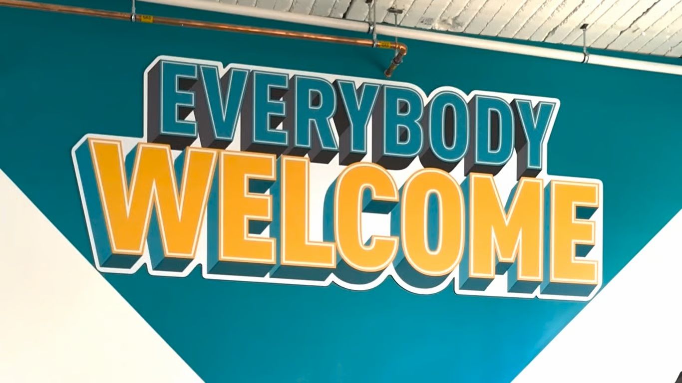 Wandgrafik mit grossem Schriftzug EVERYBODY WELCOME in Gelb und Türkis.