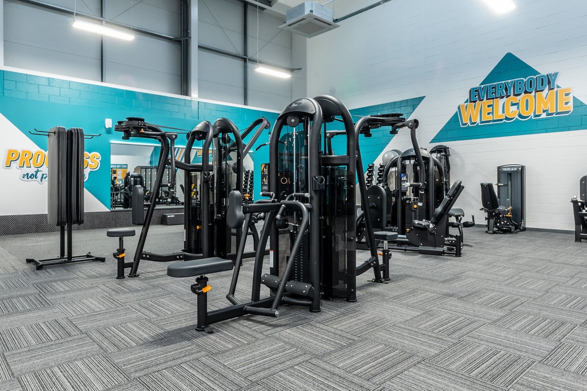 PureGym Port Talbot: Rows of resistance training machines, free weights, and rubberized flooring in a gym.