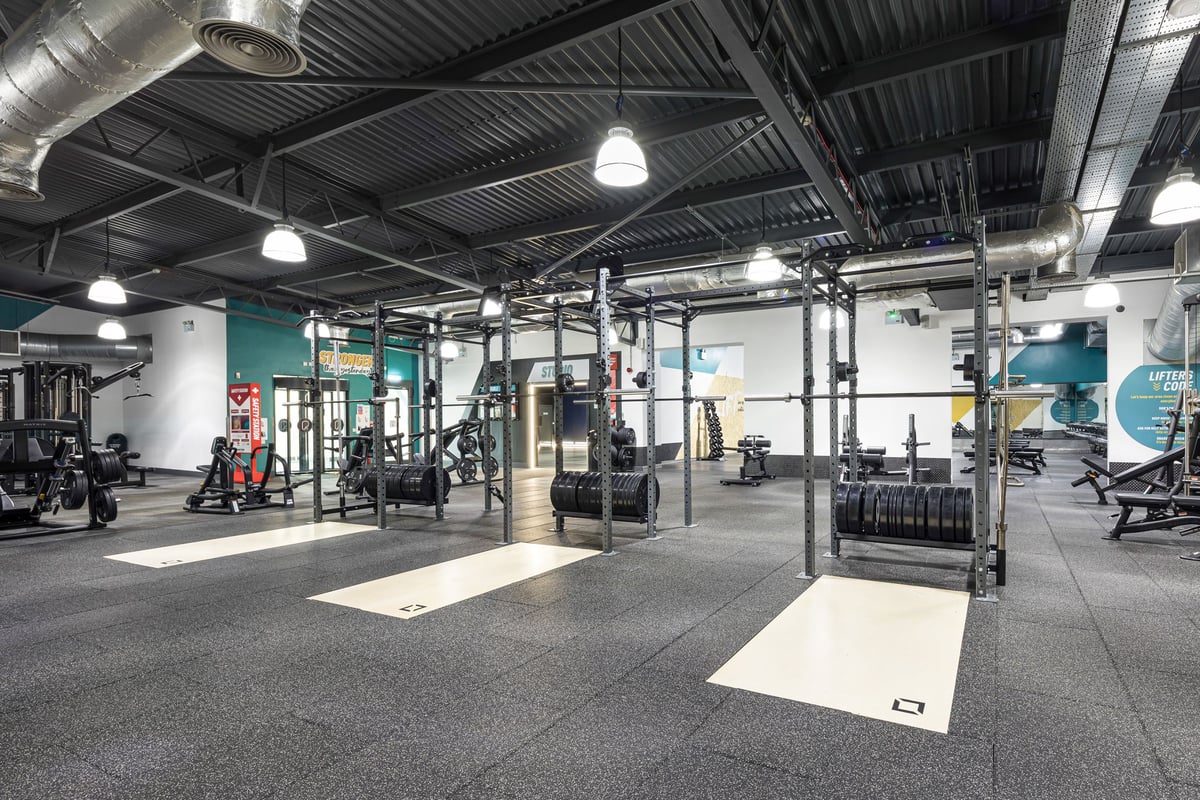 PureGym Dudley Tipton: Squat racks, weight plates, benches, rubberized flooring in a warehouse-style gym interior.