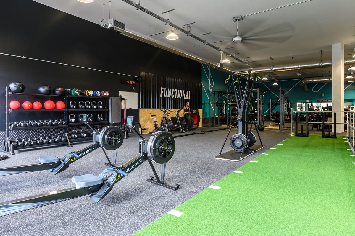 PureGym Bath Spring Wharf: Fitness studio with weight racks, kettlebells, medicine balls, turf area, and wall graphics.